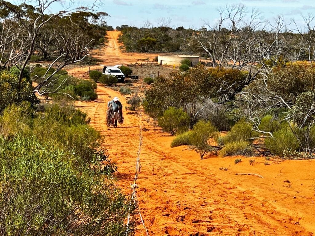 Man walking up a hill in the outback carrying equipment | Featured Image for Critical Zone Observatory Project Kicks off at Calperum Page by TERN.